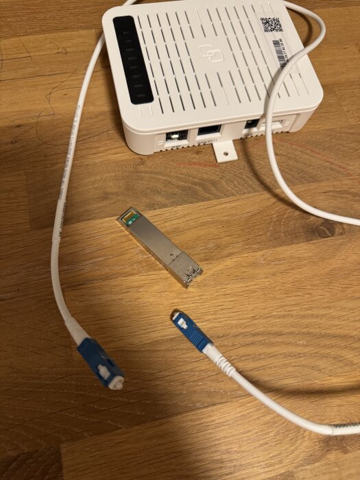 Mediaomvandlare från Telia med optisk kabel och en SFP-modul på ett träbord.