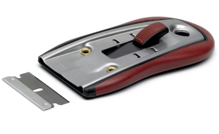 Fönsterskrapor med rött handtag och löst rakblad på en vit bakgrund.