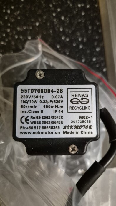 Motorenhet 55TDY060D4-2B med tekniska specifikationer på etikett, bland annat 230V/50Hz och 0.07A, samt återvinningssymbol och kontaktinformation.