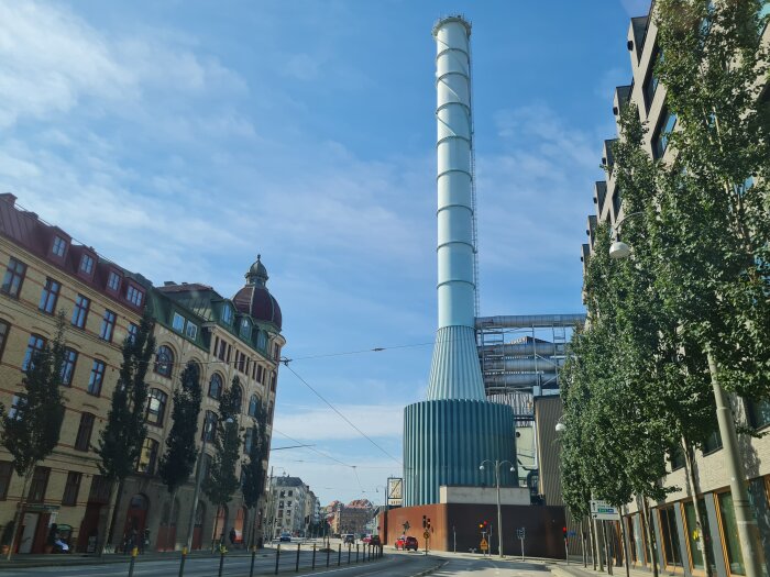 Kontrast mellan modern industribyggnad med hög skorsten och äldre bebyggelse i Göteborg.