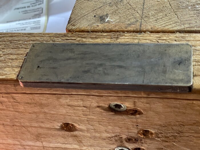 Bryne inpassat i en stadig arbetsbänk av trä, används för att vässa verktyg som saxar.