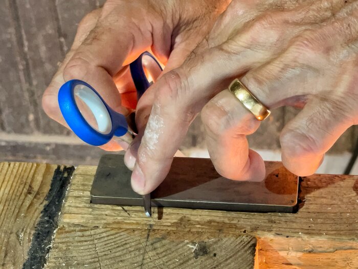 Man vässar sax på bryne inbyggt i arbetsbänk.