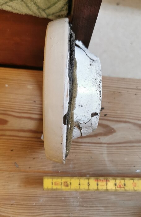 Gammalt frånluftsdon på en trävägg med synlig måttstock i bilden, relevant för planering av badrumsrenovering.