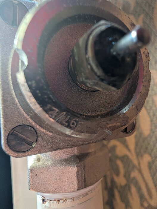 Närbild av en läckande packbox på ett rörsystem, med synlig pigg intryckt.