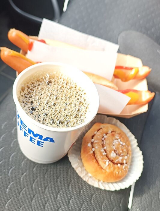 Kaffe, kanelbulle, och korv med bröd pÄ ett sÀte, en bild av en affÀrslunch.