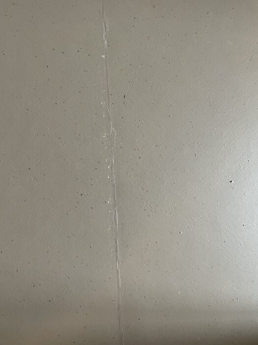 Spruckna svetsskarvar i ljus linoleummatta visar bristfälligt golvutförande med repor och ojämnheter.