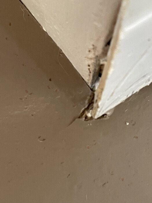 Spricka i linoleummatta vid hörn, där mattan är pressad ner och har spruckit, vilket visar på dåligt utfört arbete.