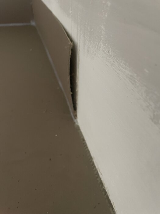 Linoleummatta med spricka i hörn och uppvik som lossnat, visar dåligt utfört arbete på golvet.