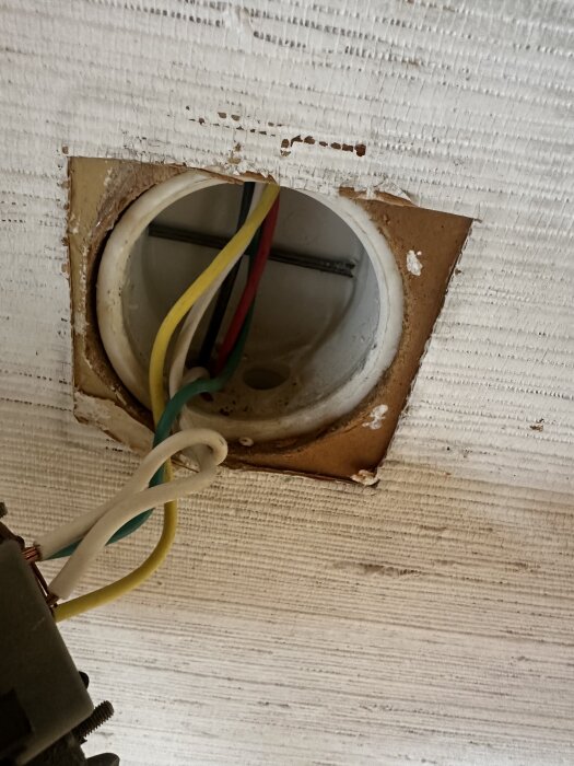 Elektrisk kopplingsdosa i tak med flera färgade kablar sammankopplade inför byte till krondimmer.