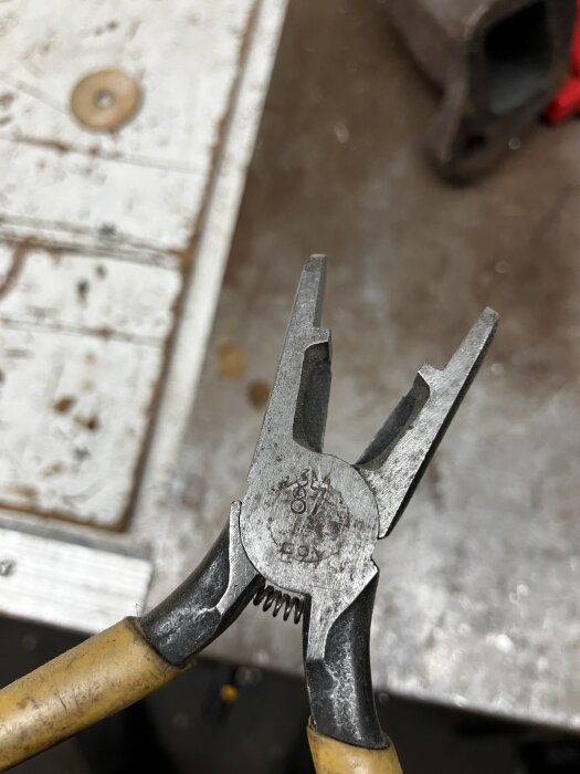 Avbitartång med annorlunda spets som är avrundad och lämnar ett mellanrum när stängd, med ett äldre verkstadsbord i bakgrunden.