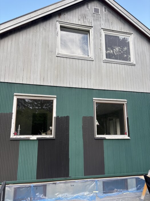 Hus med träfasad som delvis är ommålad, visar färgprover i olika nyanser. Gamla bubblor och slitaget syns. Diskussion om att rädda aluminiumdelen.