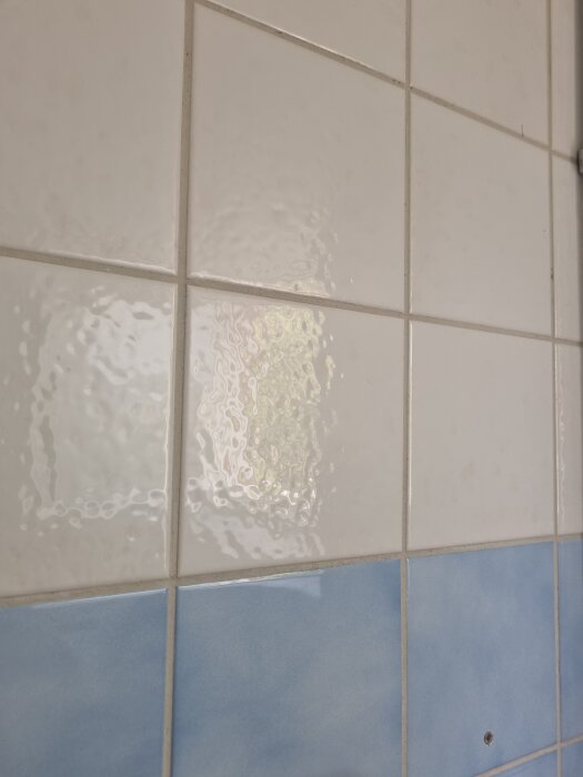 Vita och blå kakelplattor på väggen i en tvättstuga, några vita plattor behöver ersättas enligt inläggsförfattaren.