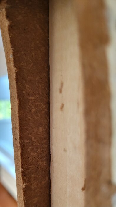 Närbild av en träfiberskiva med 10 mm tjocklek monterad på träreglar i en vägg. Skarven mellan skiva och reglar syns tydligt.