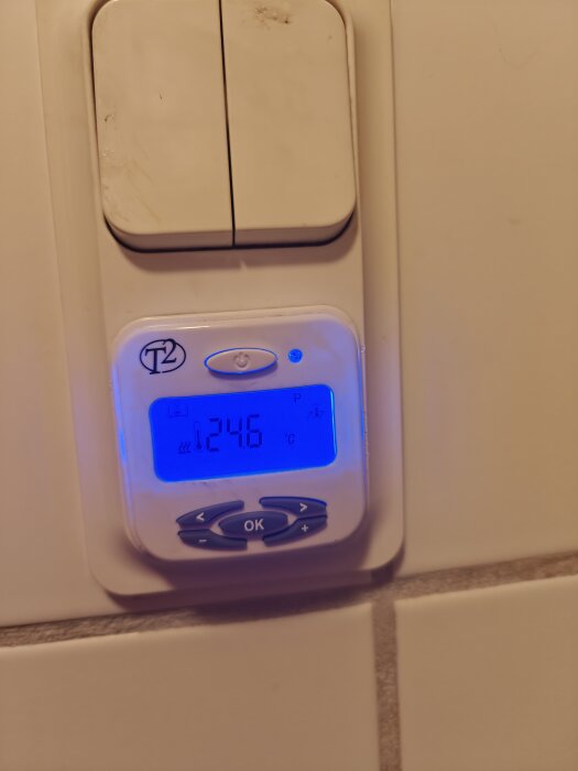 T2 termostat med display som visar 24,6°C, blå belysning och knappar för inställning.