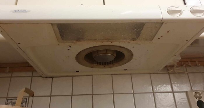 Köksfläkt undersida med avlägsnat filter, visar fläkt och smutsig yta.