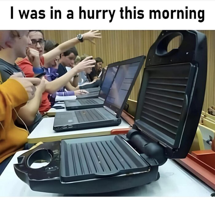 Studenter i en föreläsningssal med bärbara datorer, där en har en öppen smörgåsgrill istället för en laptop.