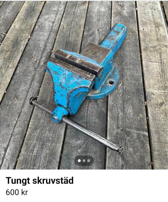 Blått tungt skruvstäd av märket Peddinghaus på en träyta, säljes för 600 kr.