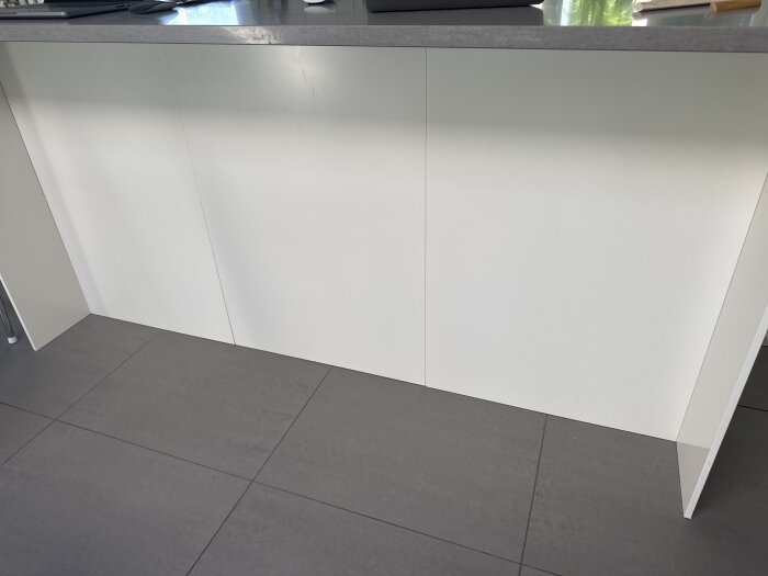 Vit köksö i ett IKEA-kök med MDF-täckskivor på baksidan, uppdelade i sektioner, som diskuterar behovet av att ersätta delar som inte gulnar.