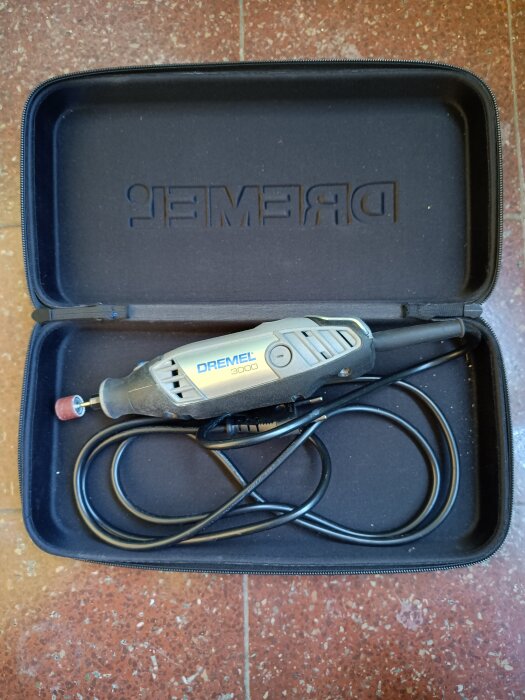 Dremel 3000 multifunktionsverktyg i en svart väska, sett uppifrån, med sladd och sliphuvud.