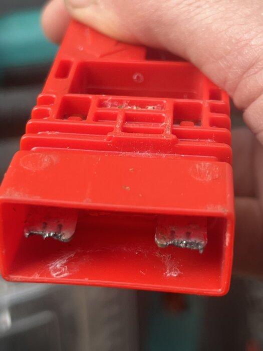 Röd nyckelkomponent till en äldre Bosch Rotak elgräsklippare, med frätsläpp på bläcket, fotograferad i närbild.