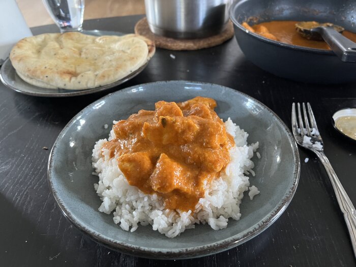 Butterchicken med ris och naanbröd på en tallrik, serverad vid ett bord.