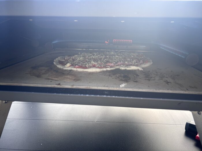 Pizza i ugn med tomatsås och ost under bakning.