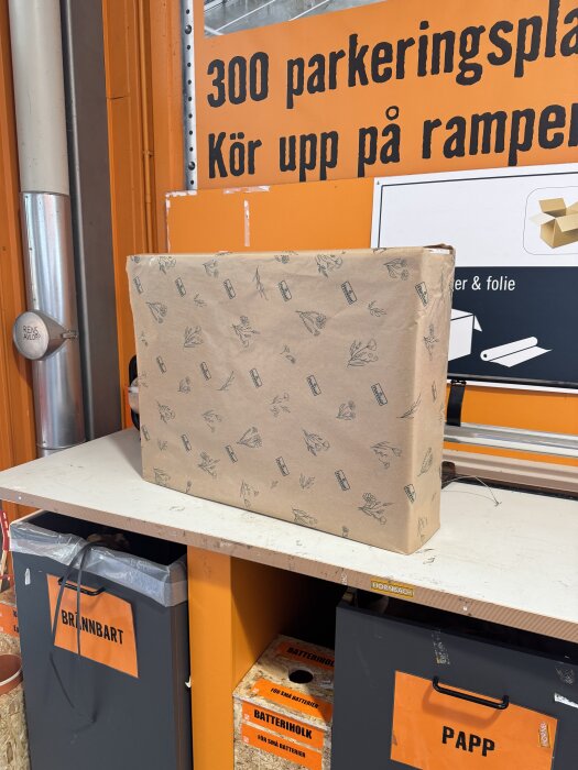 Inslaget paket på en bänk i en byggbutik, skylt med texten "300 parkeringsplatser".