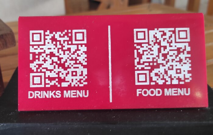 Två QR-koder på röd bakgrund, en för dryckesmenyn och en för matmenyn på en restaurang i Dar es Salaam.