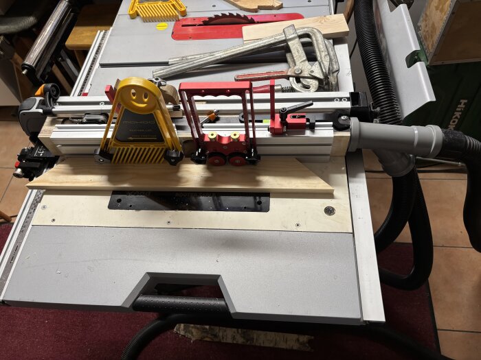 Sågbord med cirkelsåg och montageverktyg, träbit under bearbetning.