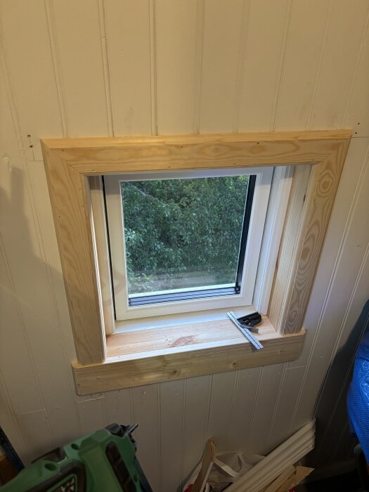 Nytt fönster med nyinstallerat träfoder och verktyg på fönsterbrädan.
