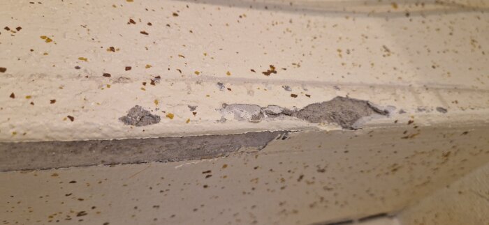 Färgad och sprucken väggyta med fläckar och avskalat puts i en pågående renovering av tvättstuga.