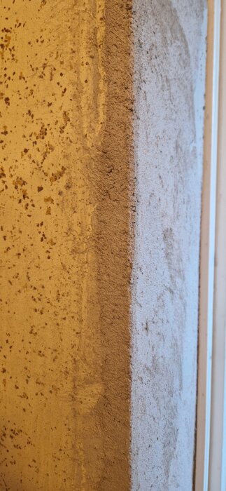 Närbild på en vägg med olika ytor, där en del av putsen är ojämnt applicerad, i en renoverad tvättstuga.