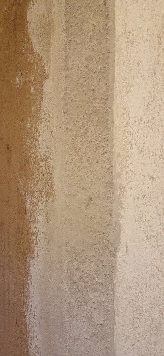 Bild av ojämna väggryggar med olika putsfärger, från en renovering i en tvättstuga där väggar har tagits bort och delvis putsats om.