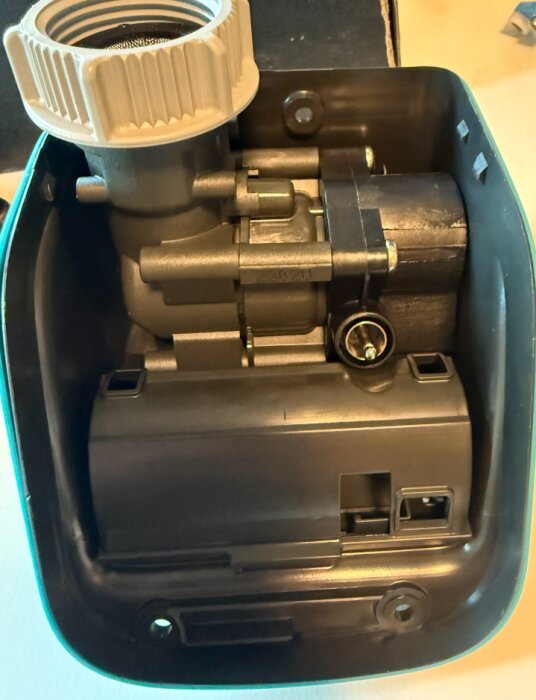 Reservdel från Gardena med ventilhus och batterihållare inuti ett plastskal, används vid byte och reparation av trädgårdskomponenter.