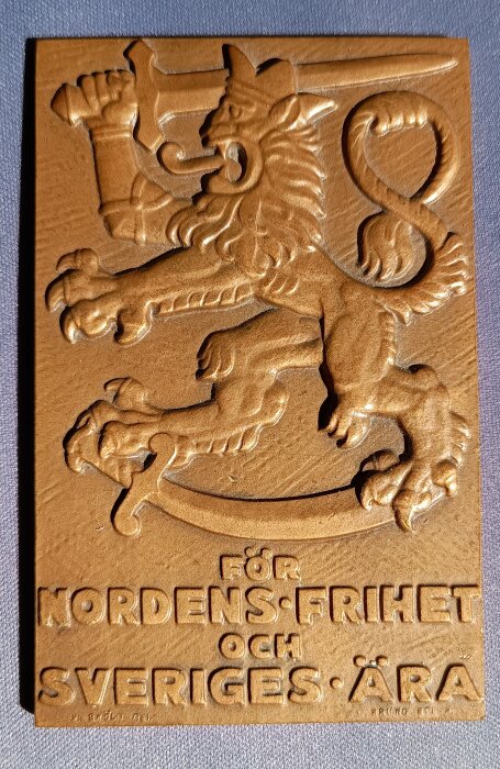 Relief med ett lejon som håller ett svärd, text "För Nordens Frihet och Sveriges Ära", till minne av de som kämpade för Finlands frihet.