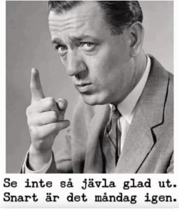 En man i kostym pekar med fingret, allvarligt ansiktsuttryck. Text: "Se inte så jävla glad ut. Snart är det måndag igen.