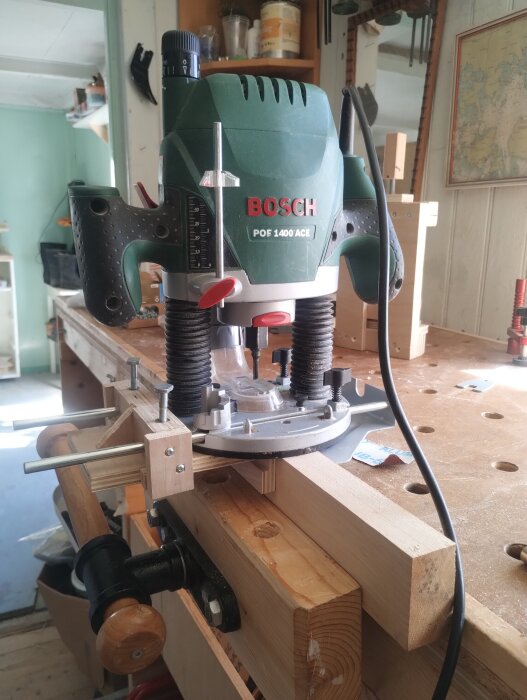 Handöverfräs på arbetsbänk med extra anslag i trä för ökad stabilitet vid fräsning av tapphål.