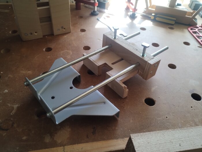 Extra anslag till handöverfräs med metall- och träkomponenter på en arbetsbänk för fräsning av tapphål.