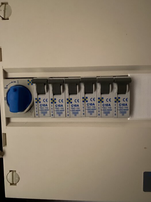 Säkringsskåp med flera brytare och en blå vridbrytare till vänster, märkt C10A TSC-110 230/400V.