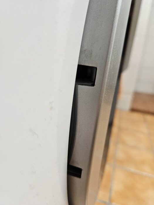 Närbild av en tvättmaskins luckfel, som visar handtaget som är felplacerat och inte tätt stängt mot maskinkroppen.