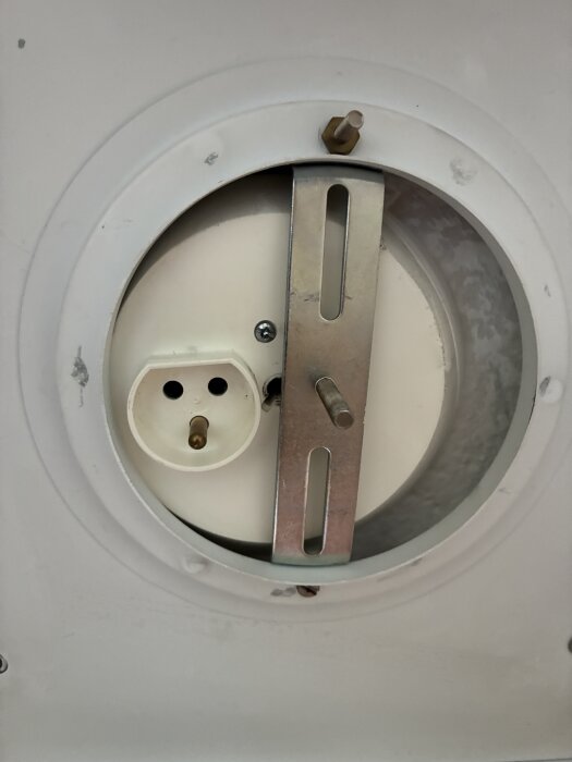 Takanslutning med muttrar och skruvar, visar en ojordad lamphållare och en metallplattas placering i förhållande till eluttaget.