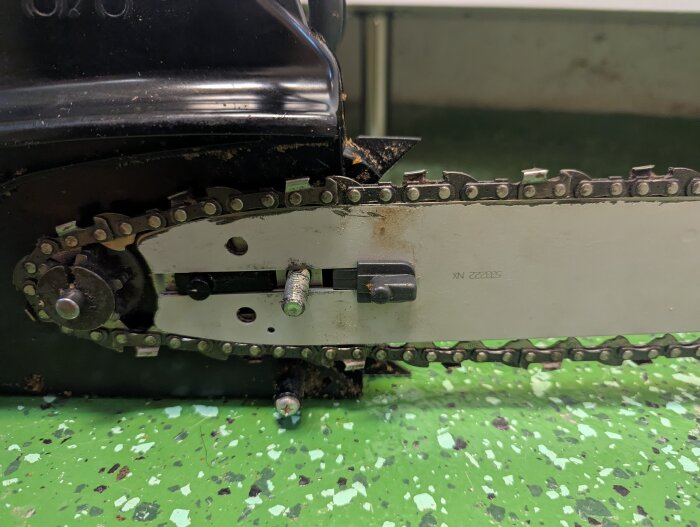 Motorsåg med monterad kedja och svärd på golv.