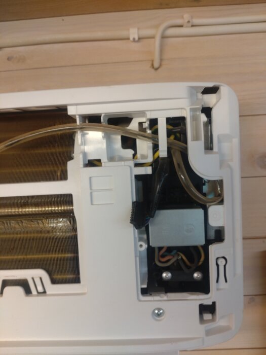 Luftvärmepumpens innerdel efter lagerbyte i snickarverkstaden, med exponerade komponenter och ledningar.