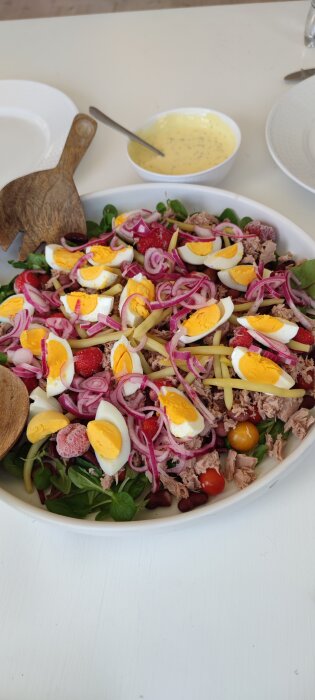 Tonfisksallad med kokt ägg, rödlök, jordgubbar och bönor, serverad med en kvarg- och bea-dressing i bakgrunden.