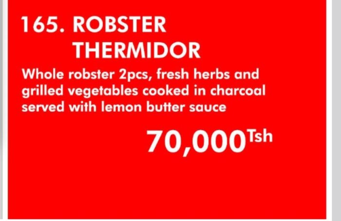 Menybild visar "Robster Thermidor" med två bitar, färska örter, grillade grönsaker och citron- och smörsås för 70 000 Tsh.