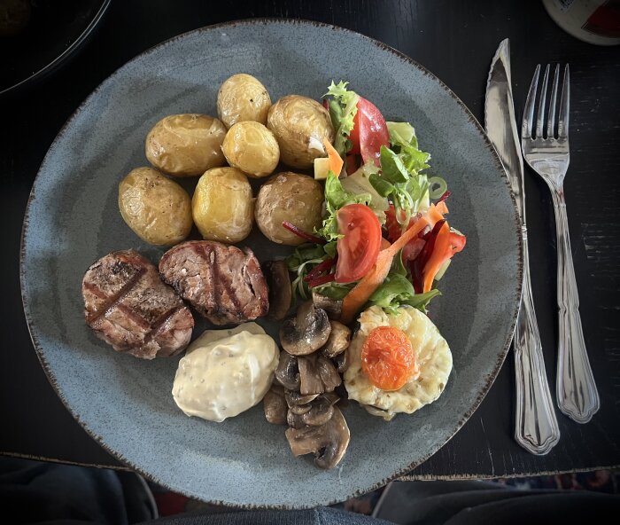 Grillad fläskfilé med sallad, egenodlad ugnsstekt potatis, smörstekta champinjoner, squash med ost och tomat samt bearnaisesås på tallrik.