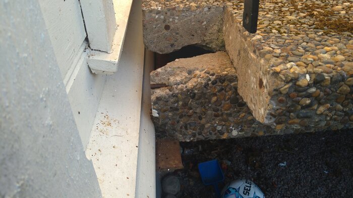 Betongtrappa med spricka vid hörnet av översta trappavsatsen. Väl synlig armering och delvis vittrat vangstycke vilande på metallvinkel.