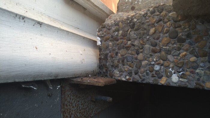 Betongtrappa med ett utsågat hörn på översta trappavsatsen, där vangstycket vilande på en rostig metallvinkel visar synlig armering.