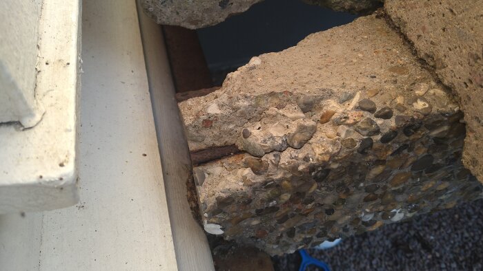 Betongtrappa med synlig armering vid hörnet av översta trappavsatsen där vangstycket visar tecken på vittring.