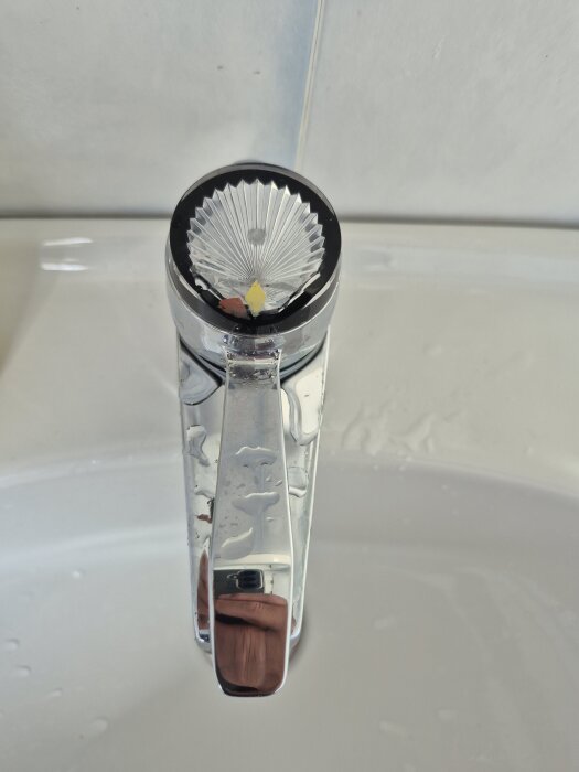 Läckande badrumsarmatur med vatten på handtagets toppdel.